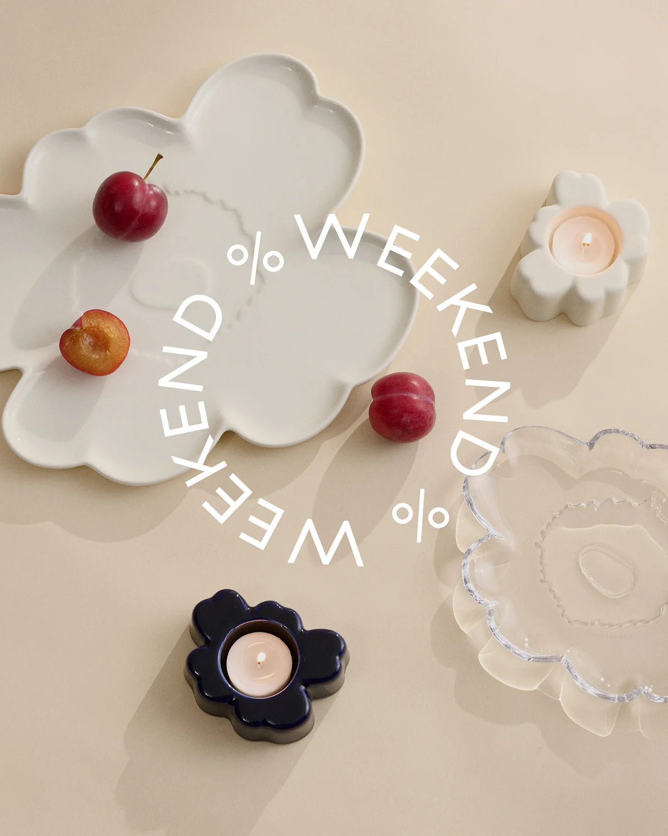 Ozdobne talerze i świeczniki w kolorze białym, niebieskim i przezroczystym szkle z śliwkami na beżowym tle. Biały tekst 'Weekend %'.