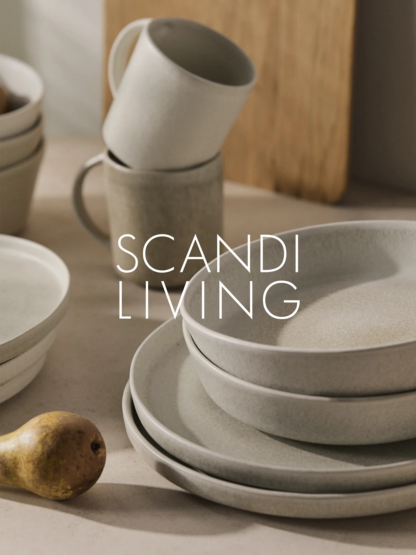 Ułożone w stos beżowe naczynia ceramiczne, kubki i gruszka z napisem "SCANDI LIVING".
