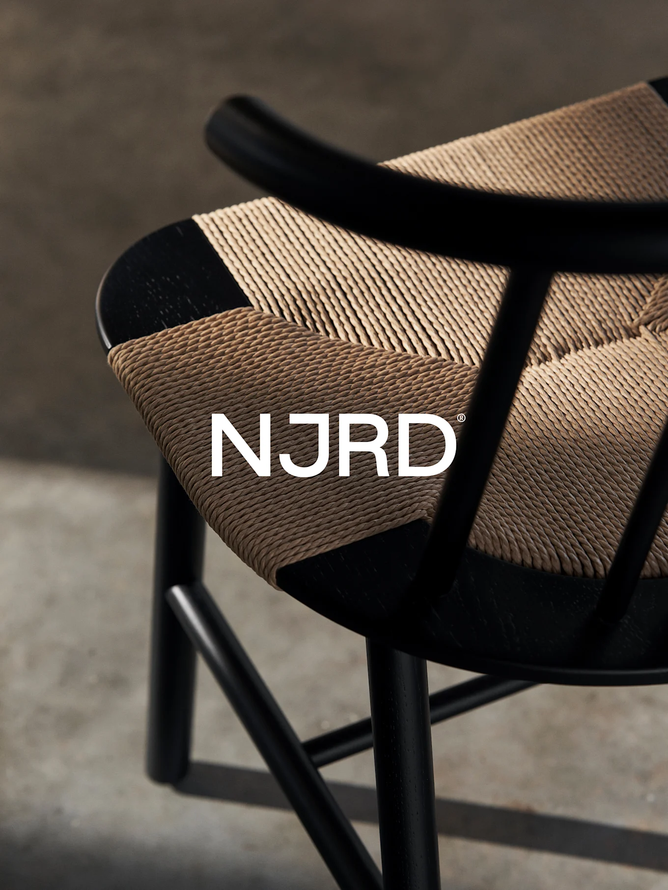 Zbliżenie czarnego krzesła z plecionym jasnobrązowym siedziskiem, z białym logo 'NJRD'.