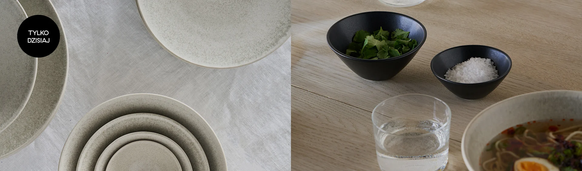 Stos ceramicznych talerzy na obrusie z napisem 'Tylko Dzisiaj'. Obok miseczki z ziołami i solą, szklanka wody, ramen.