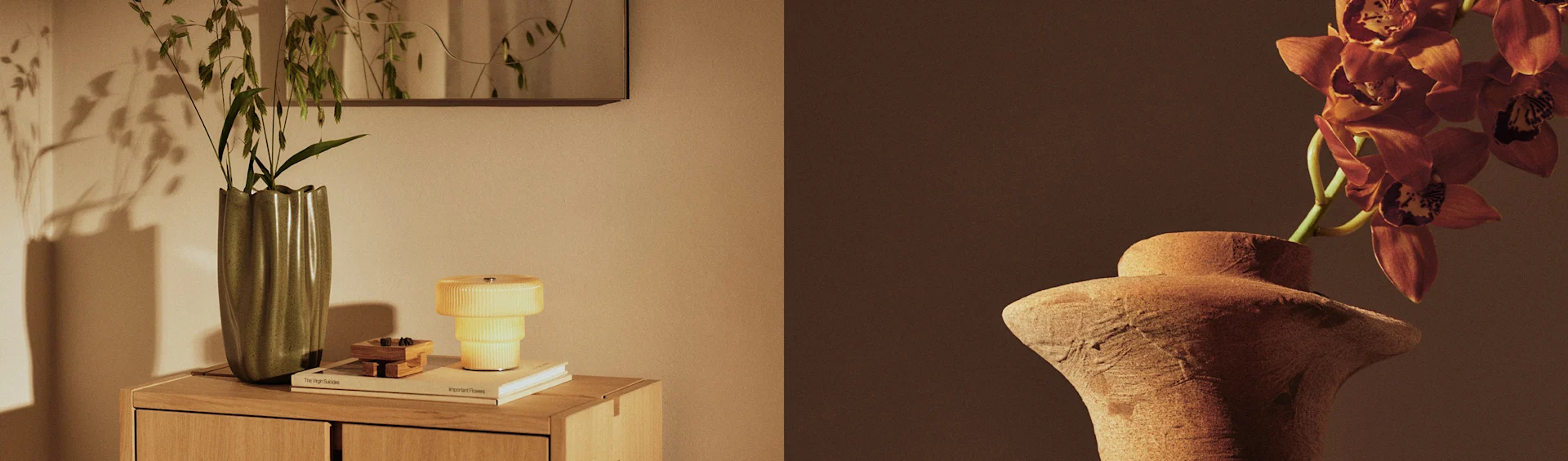 Dwie wazony z roślinami, jeden zielony wazon z liśćmi na szafce obok żółtej lampy, i jeden terakotowy wazon z pomarańczowymi storczykami.