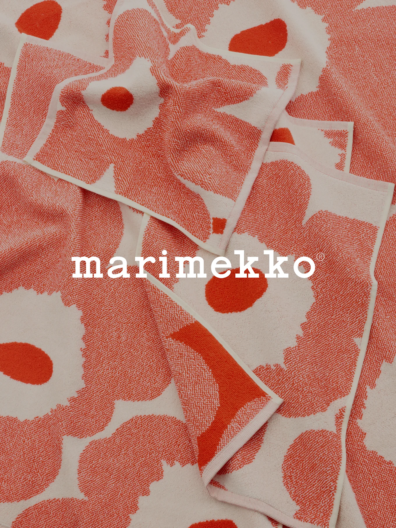 Złożone ręczniki we wzory koralowo-białe z logo Marimekko.