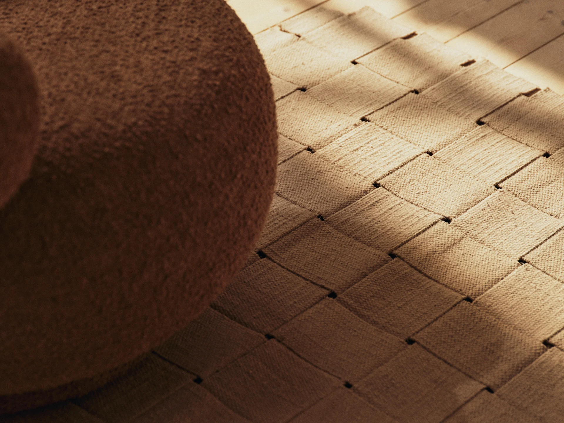 Brązowe meble bouclé, tkany dywan i drewniana podłoga z nasłonecznionymi cieniami.