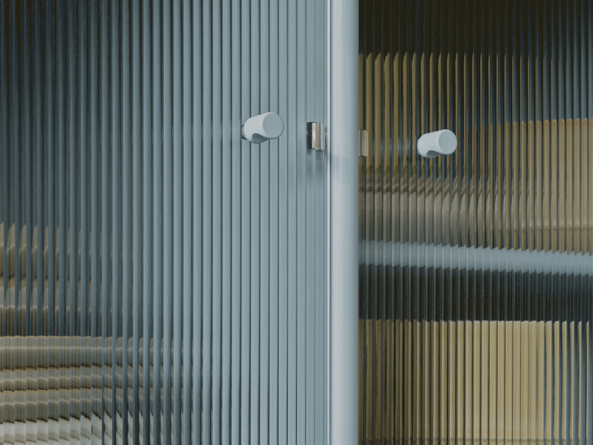 Zbliżenie na drzwi ze szkła ryflowanego z dwoma jasnymi okrągłymi uchwytami, ukazujące zniekształcone kolory przez fakturę.