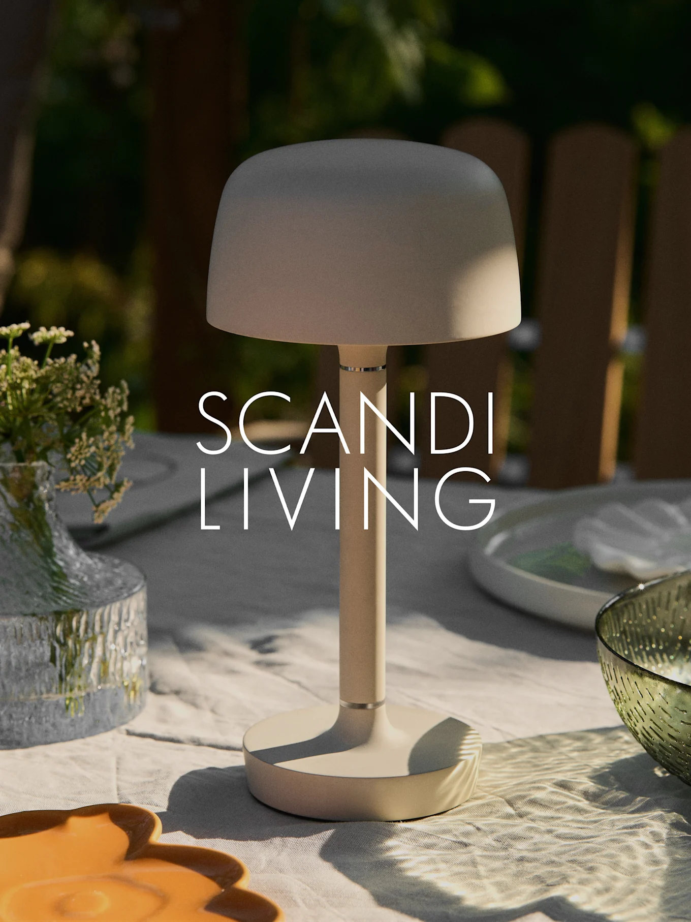 Beżowa, nowoczesna przenośna lampa stołowa na stole ogrodowym z wazonem kwiatów i naczyniami. Tekst "SCANDI LIVING".