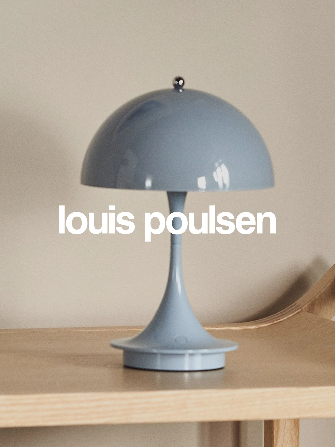 Jasnoniebieska lampa stołowa w kształcie grzyba na drewnianej powierzchni z napisem 'louis poulsen'.