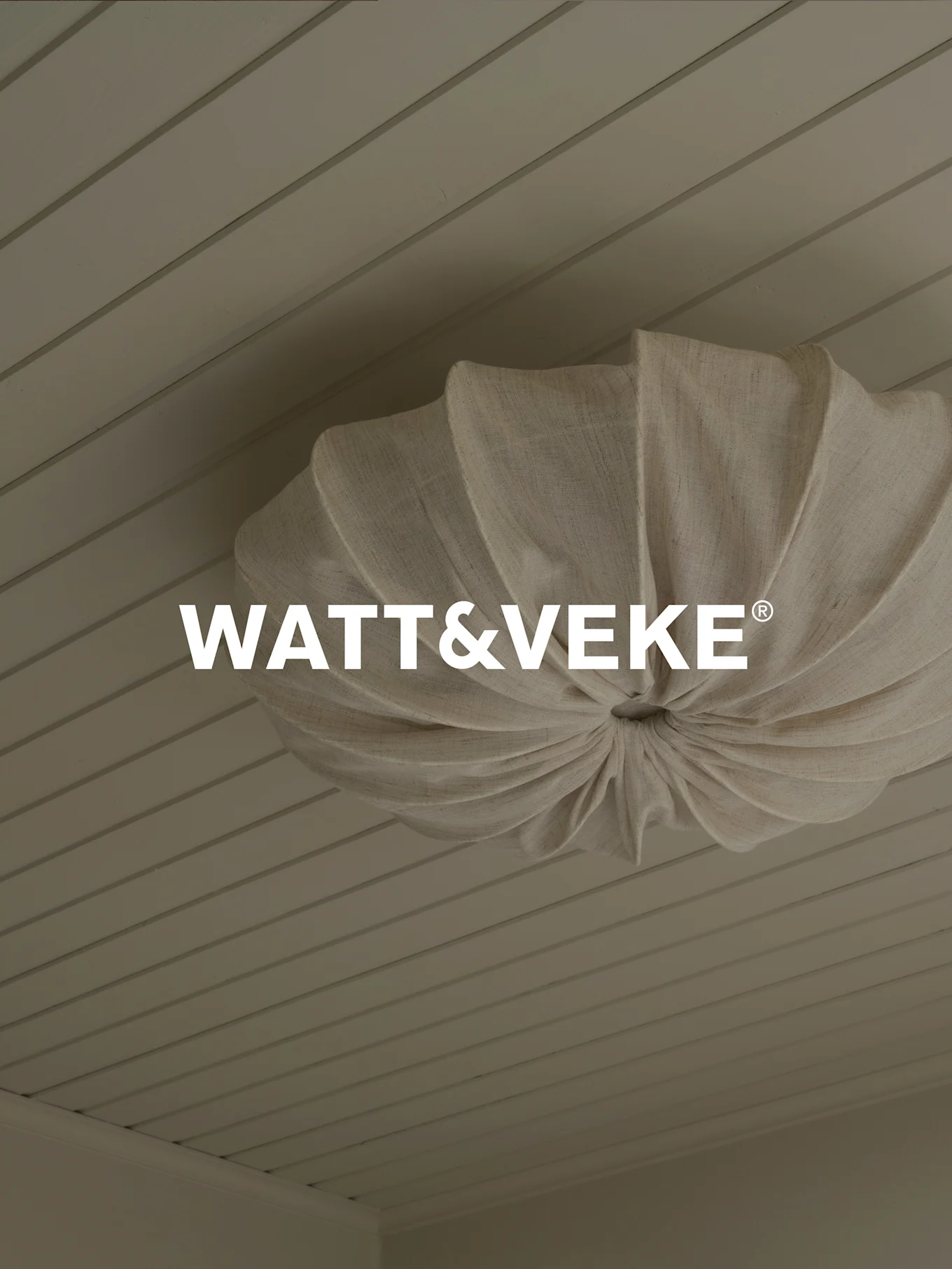 Logo WATT&VEKE® nad plisowaną lampą sufitową z naturalnego materiału na jasnym drewnianym suficie.
